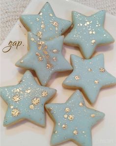 four blue and gold decorated cookies on a white plate