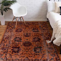 an orange area rug in front of a white bed