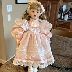 a doll sitting on top of a wooden table next to a kitchen counter and cabinets