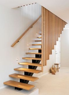 there is a wooden stair case in the house with white walls and flooring on it