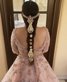 the back of a woman's head wearing a pink dress with gold jewelry on it