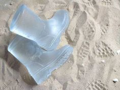 two plastic shoes are laying in the sand