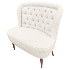 an upholstered white chair with wooden legs and buttons on the armrests