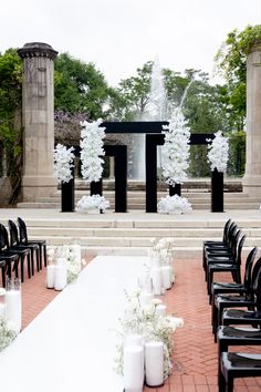 an outdoor ceremony setup with black chairs and white flowers