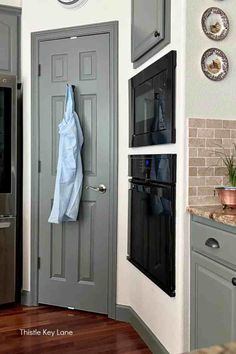 a gray door in a kitchen with plates on the wall and a clock above it