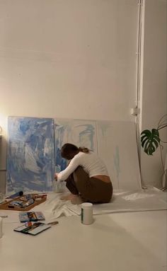 a woman is sitting on the floor painting