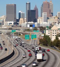 cars are driving on the highway in front of large city buildings and tall skyscrapers