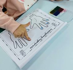 a young child is making a hand sign on a sheet of paper with colored crayons