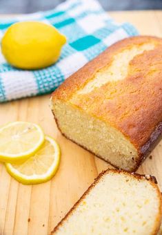 a loaf of lemon bread sitting on top of a cutting board next to sliced lemons