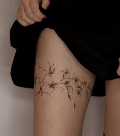 a woman's thigh with flowers tattooed on the lower part of her leg,