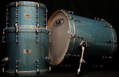 two blue drums sitting next to each other on top of a black surface with silver rivets