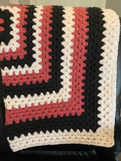 a crocheted blanket sitting on top of a black chair