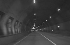 a car driving through a tunnel with lights on at the end and one light in the middle