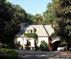 a white car parked in front of a house surrounded by trees and bushes on a sunny day