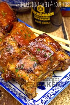 two pieces of meat on a blue and white plate with chopsticks