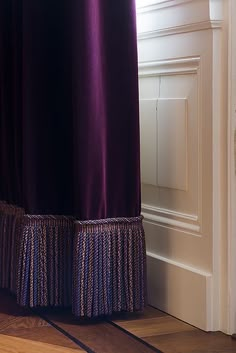 a purple curtain is hanging in front of a white door with a wooden floor next to it