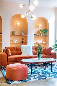 a living room with orange couches and blue rugs on the hardwood flooring