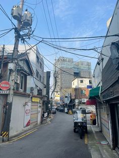 an empty street with lots of buildings and power lines above the road in front of it