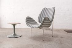 two chairs sitting next to each other on top of a cement floor in front of a white brick wall