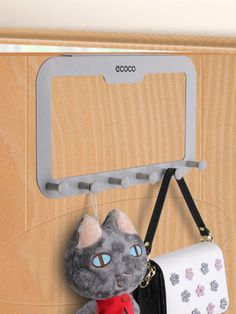 a stuffed animal hanging from a hook on a wooden door with a purse attached to it