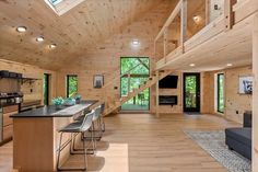 a kitchen and living room inside of a wooden house with stairs leading up to the second floor