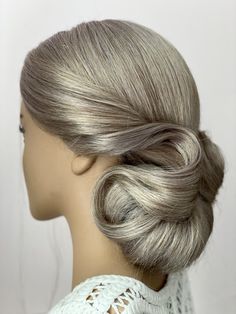 a woman's hair is styled in a low bun