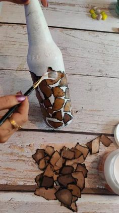 someone is painting an animal head on a wine bottle with paintbrushes and paper