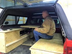 a man sitting in the back of a truck with a table on it's seat