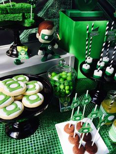 a table topped with lots of desserts and green candies on top of plates