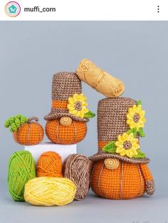 crocheted pumpkins with hats and flowers on them are sitting next to yarn balls