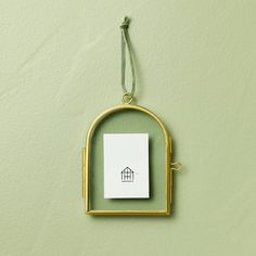 a piece of paper hanging from a gold frame with a house logo on the front