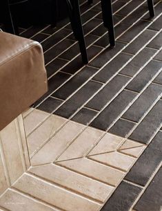 a brown chair sitting on top of a tiled floor next to a black and white table