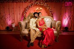 a man and woman sitting on a couch in front of a stage with red lights