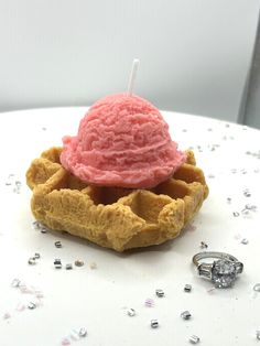 a pink ice cream sundae sitting on top of a waffle with a diamond ring