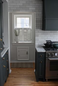 a kitchen with gray cabinets and white brick walls