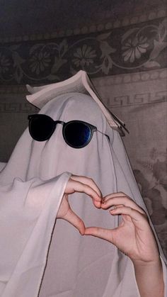 a person wearing sunglasses making a heart shape with their hands