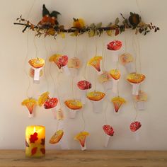 a candle and some paper decorations on a table next to a wall with birds hanging from it