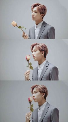 a man in a suit holding a rose up to his face