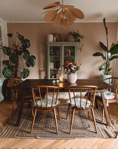 a dining room table surrounded by plants and chairs