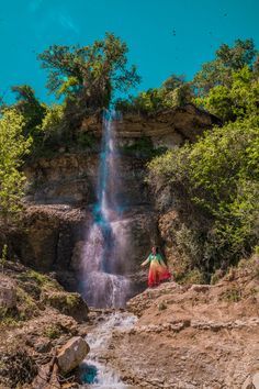 a man standing at the base of a waterfall