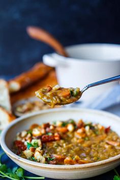 a spoon full of soup with bread in the background