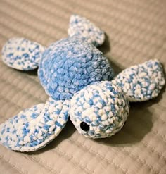 a blue and white turtle laying on top of a bed