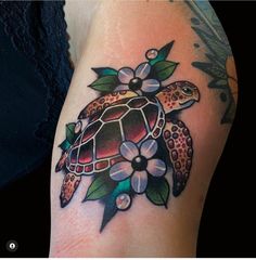 a woman's arm with a turtle and flowers tattoo on the left side of her body