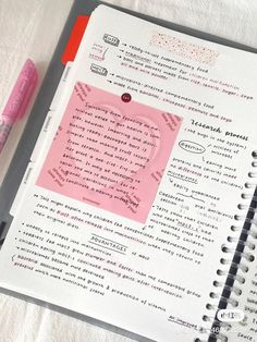 a notebook with writing on it next to a pink marker and some paper clippings