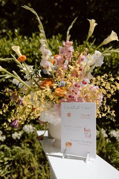 an arrangement of flowers is on display in a vase with a sign attached to it