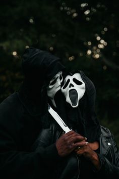 a person wearing a black and white mask with a knife in their hand while standing next to each other