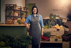 a woman in an apron standing next to vegetables