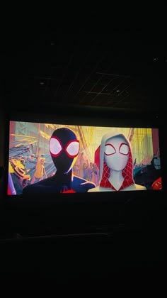 two animated characters on a large screen in a dark room