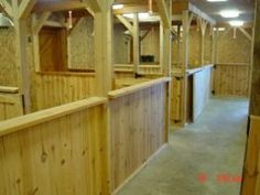 the inside of a horse stable with wooden stalls and stalls lined up against each other