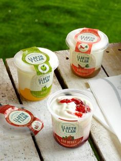 three yogurts sitting on top of a wooden table